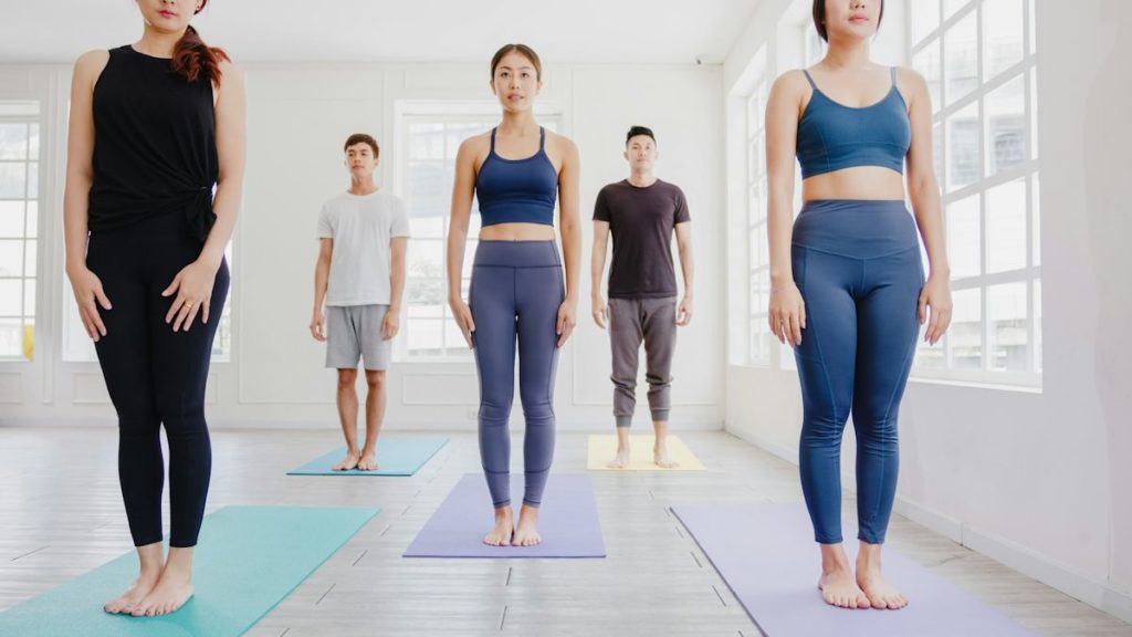 Un groupe de personnes font une pose yoga debout, les bras le long du corps.