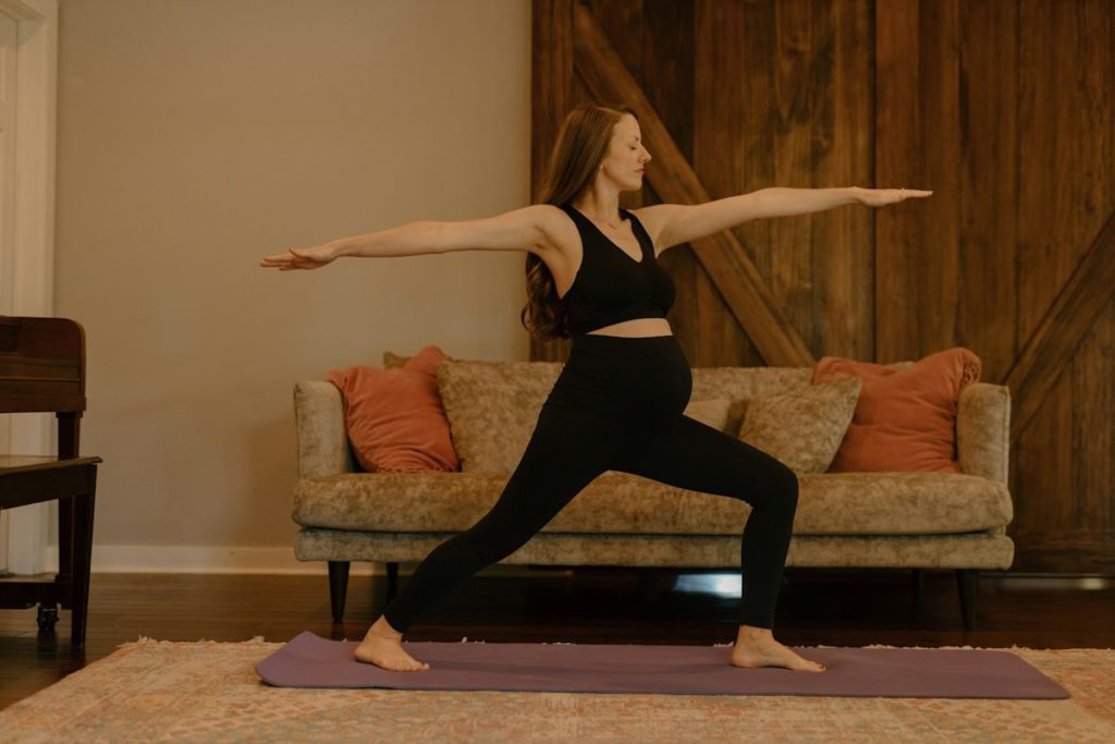 Une femme enceinte se tient debout, en pose de yoga.