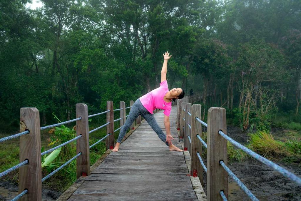 Une femme effectue une pose de yoga en forme de triangle.