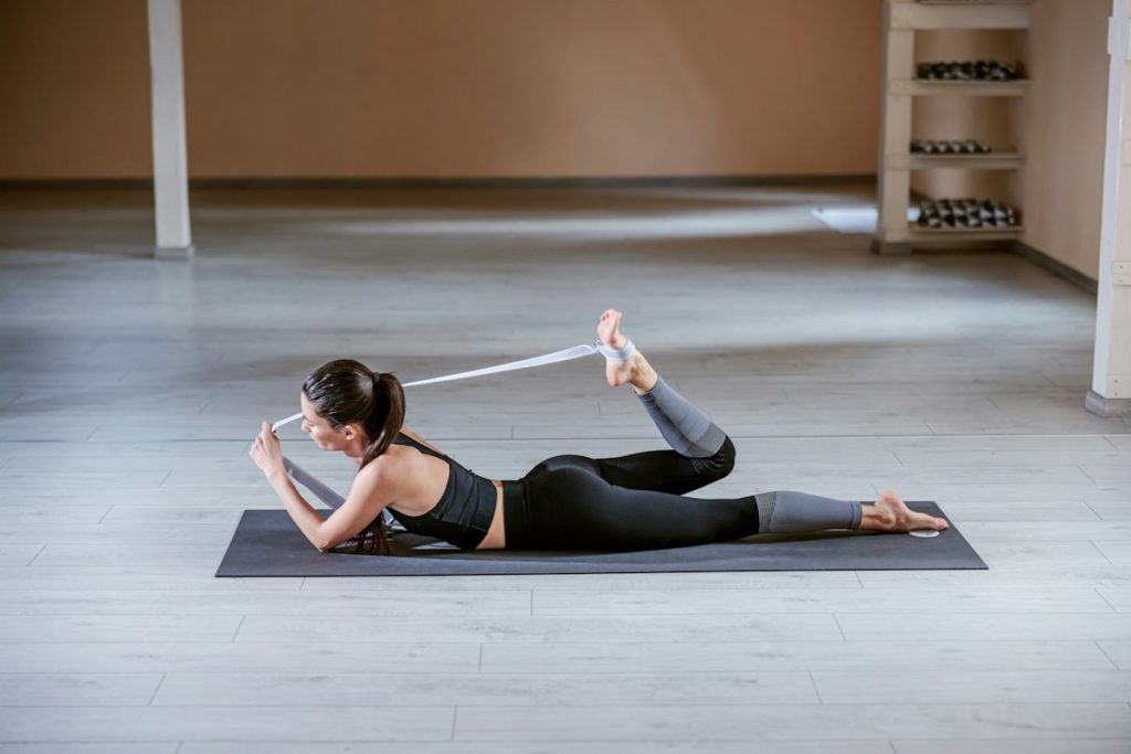 Une sportive effectue un exercice de yoga allongée sur un tapis.