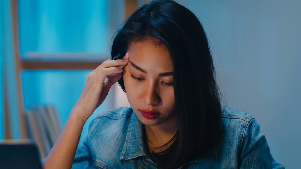 Une femme vêtue de bleu réfléchit en baissant les yeux vers le bas.