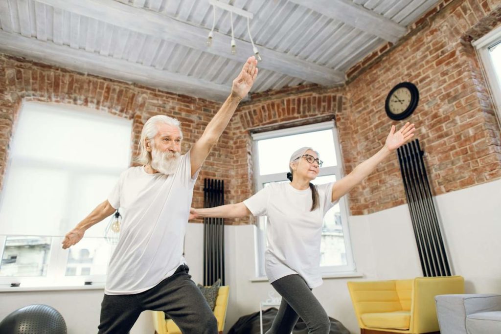 Un vieil homme et une dame font une pose de yoga.