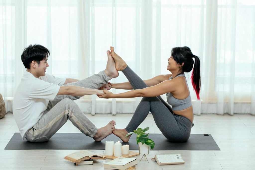 Deux personnes en position assise, tendent une jambe en daisant toucher leurs pieds.