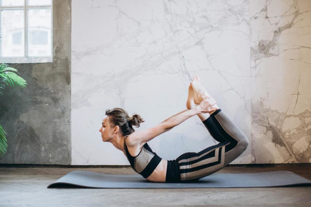 Une femme fait une posture de yoga en étirement sur le ventre.