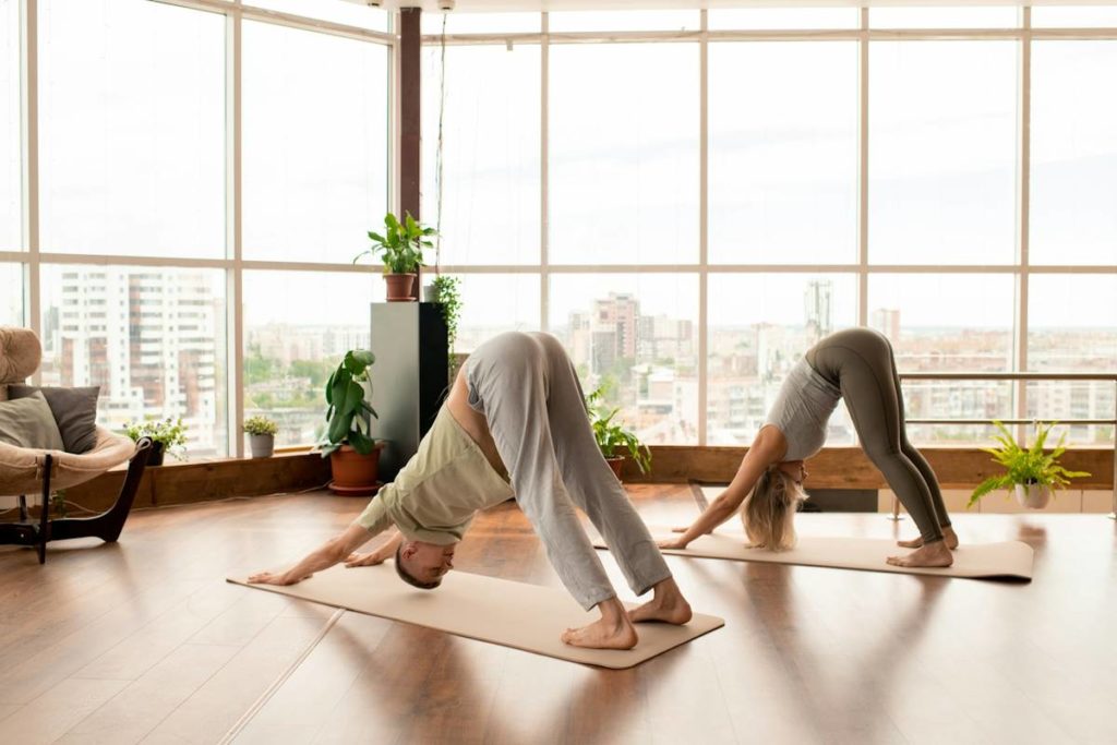 Deux personnes pratiquent le yoga dans une pièce lumineuse.