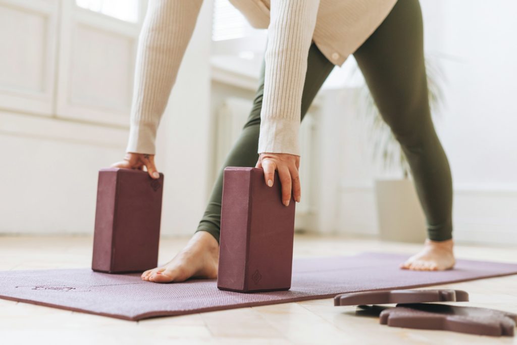 Une pratiquante de yoga s'apprête à se mettre en position de pompe avec des blocs au sol.