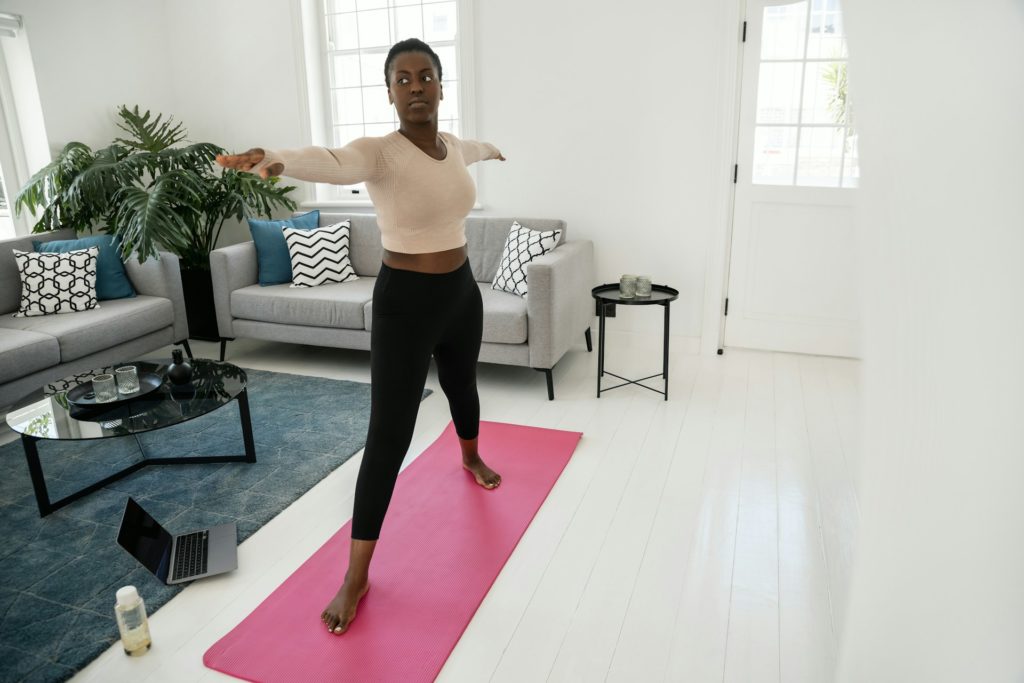 Une sportive fait du yoga dans une pièce lumineuse de couleur blanche.