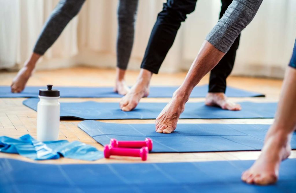 Des pratiquants de yoga photographiés depuis le sol avec leurs jambe droite tendue.