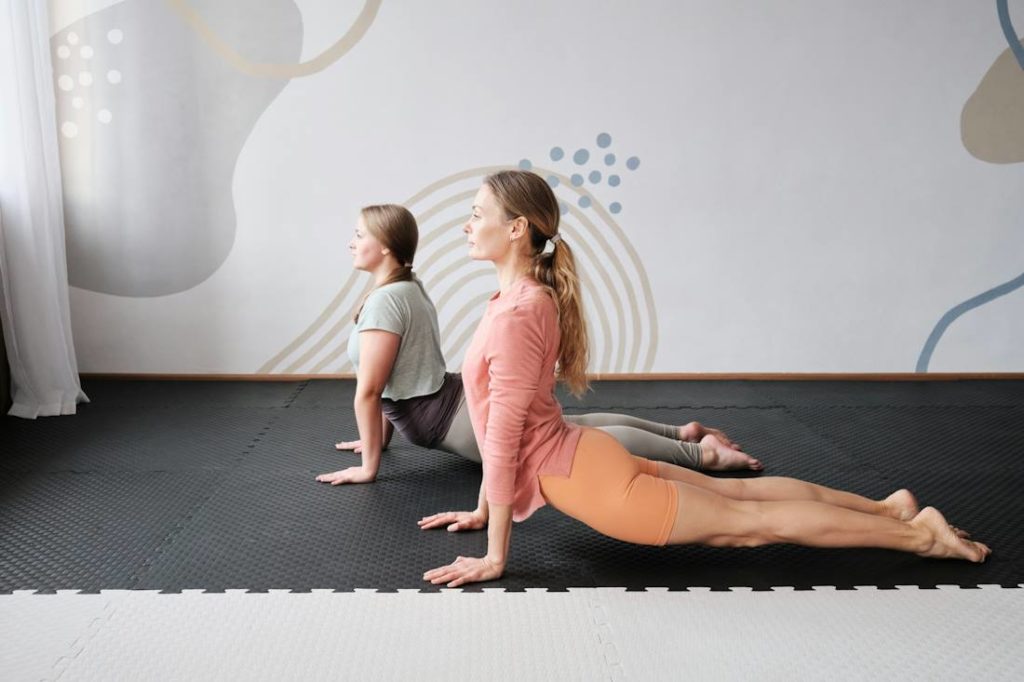 Deux pratiquantes de yoga effectuent ensemble une posture au sol.