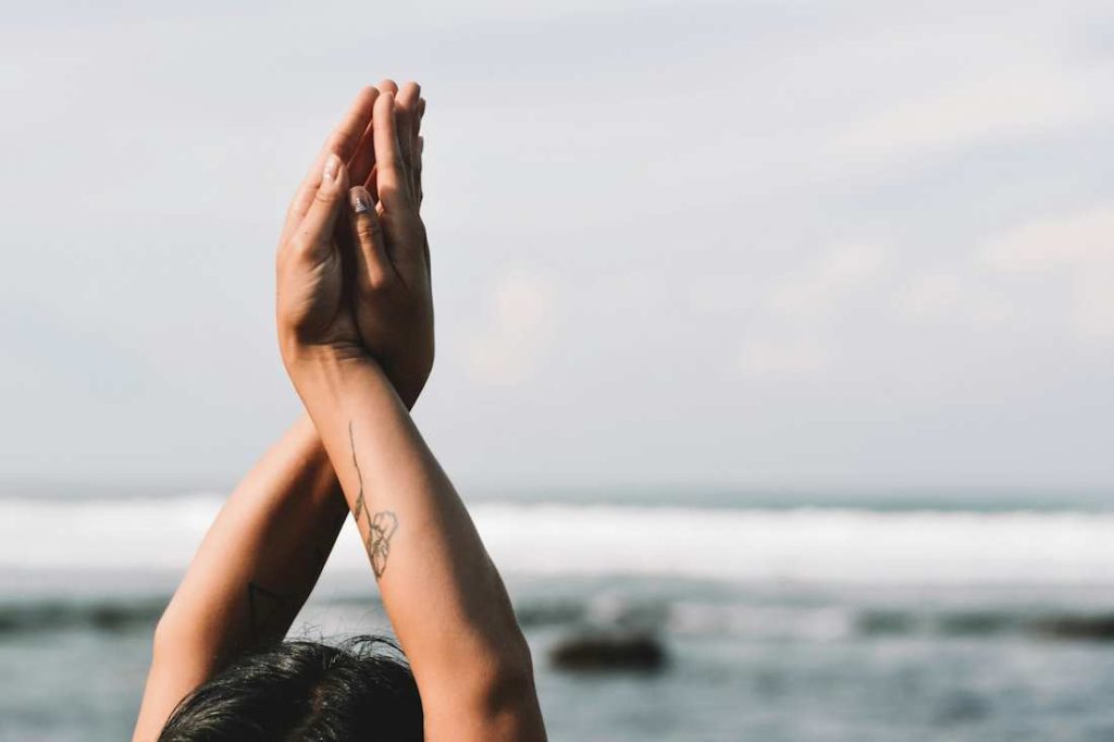 Vue sur les bras d'une personne qui fait du yoga sur une plage.