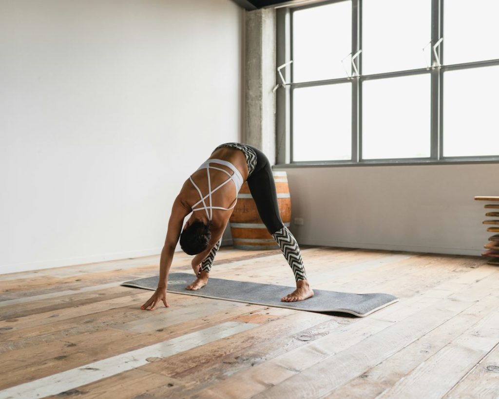 Une pratiquante dans une salle de yoga, en train de faire une posture avec les membres au sol.