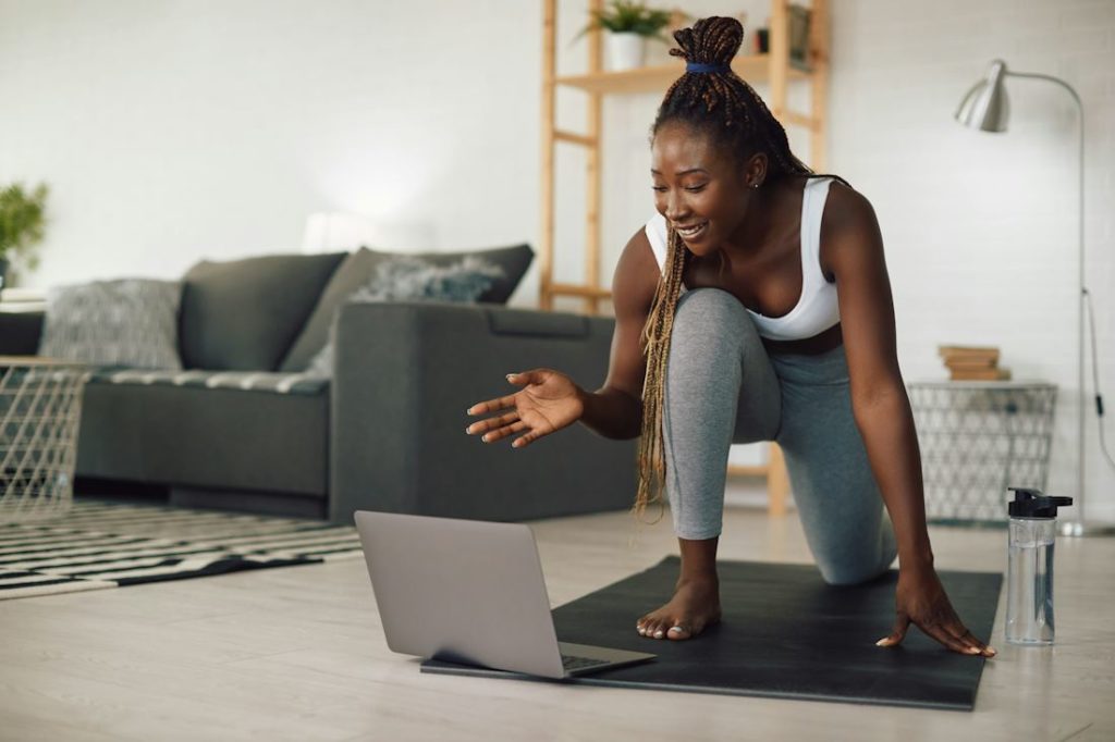 Une jolie femme fait une séance de yoga en ligne dans son salon.