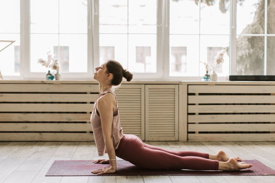 Une sportive fait une pose de yoga au sol en relevant son buste et sa tête.