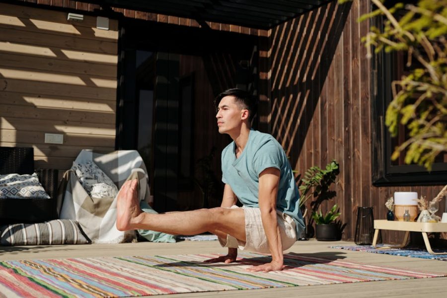 Un garçon vu de profil en train de faire une posture de yoga très difficile sur ses mains.